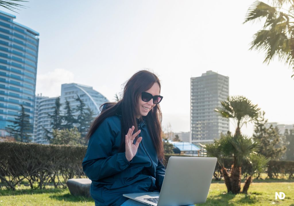 Mujer en parque en españa saludando computador nomadas digitales