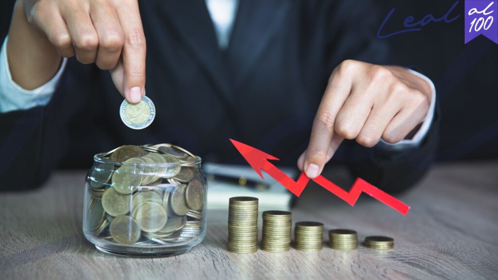 Persona coloca una moneda en recipiente de vidrio, monedas organizadas en colimnas ascendentes Visa Nómada Digital en España